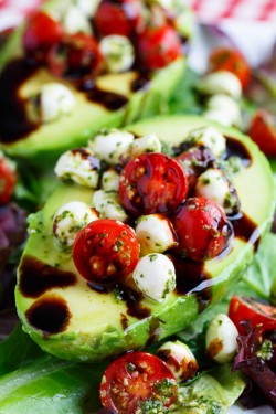 Avocados stuffed with fresh tomatoes and mozzarella tossed in basil pesto and finished with a dr ...